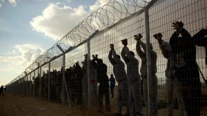 African migrants stands inside Holot detention center as others protest outside against the detention center near Ktsiot the Negev Desert in southern Israel, Monday, Feb. 17, 2014. In recent weeks, African migrants, mostly from Eritrea and Sudan, have staged a series of demonstrations demanding they be recognized as refugees, a status that would give them residency rights. Israel sees many of them as economic migrants and has tried a number of tactics to stop the migrants' influx or keep their numbers down. It has built a fence along the border with Egypt, passed a law that allows for the migrants' detention and offered financial incentives to urge them to leave. (AP Photo/Oded Balilty)